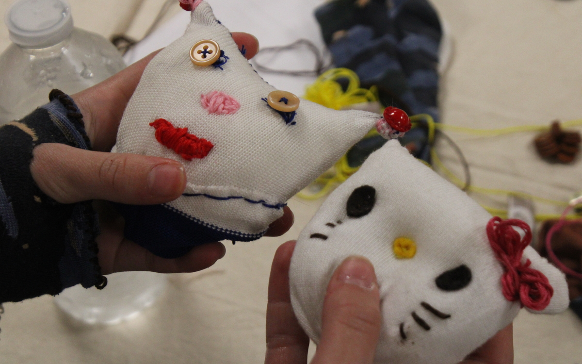 Photographies de deux mains tenant des peluches qui ont été réalisées à partir de chaussettes, avec des boutons et des fils de couleurs.