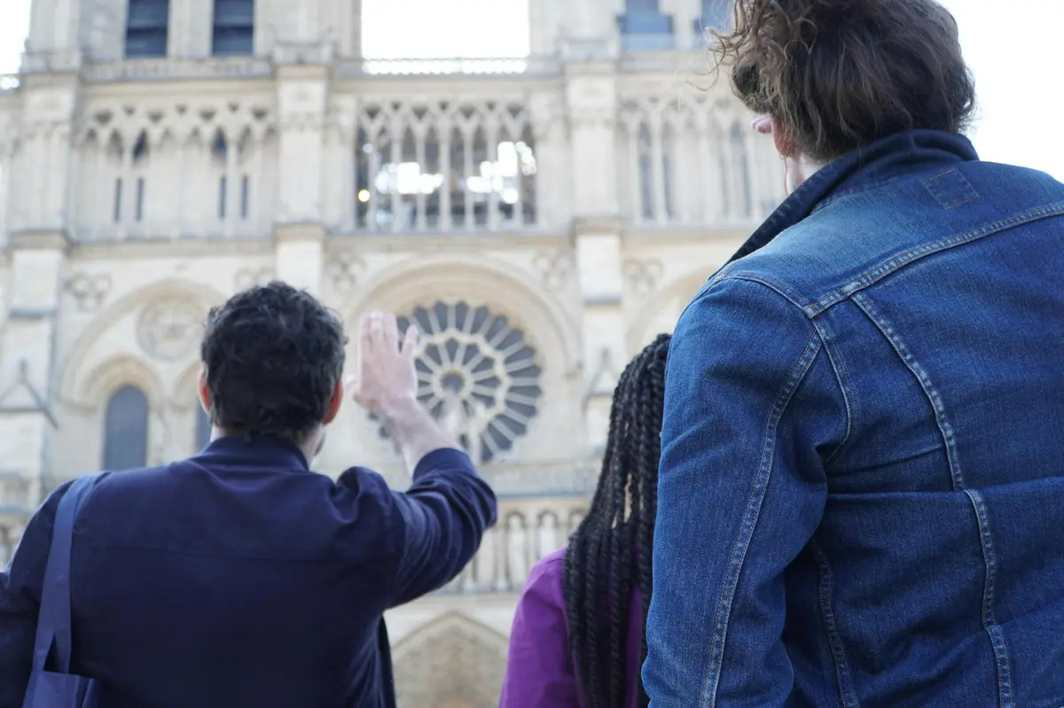 A guide explaining the facade of Notre Dame Cathedral to guests