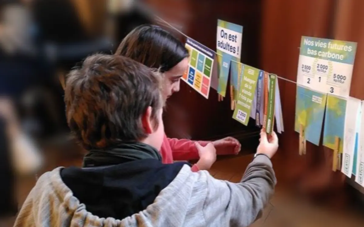 Deux enfants accrochent des cartes sur une longue ficelle