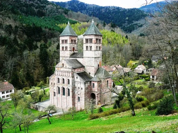 La façade de l\'abbaye de Murbach surgit parmi la forêt des Vosges