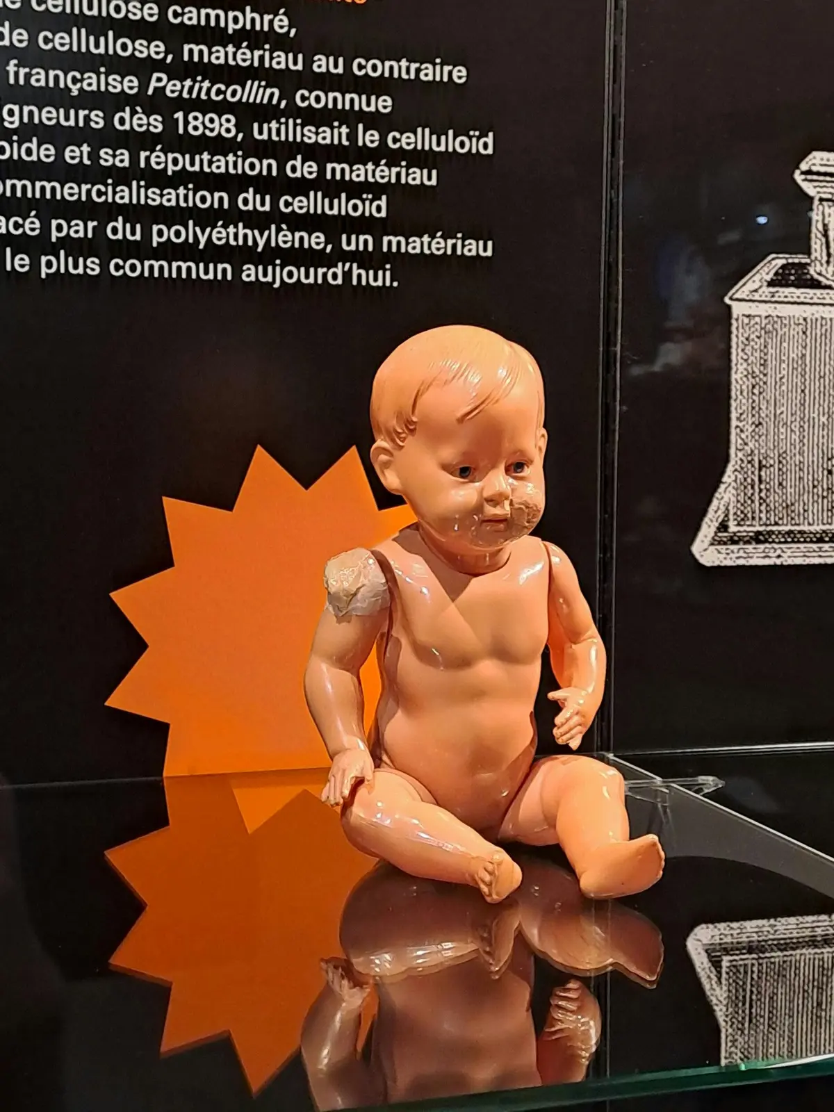 Une poupée en plastique usée et nue, dont l'épaule est abîmée, est présentée sur un fond noir avec un texte et des illustrations en français.