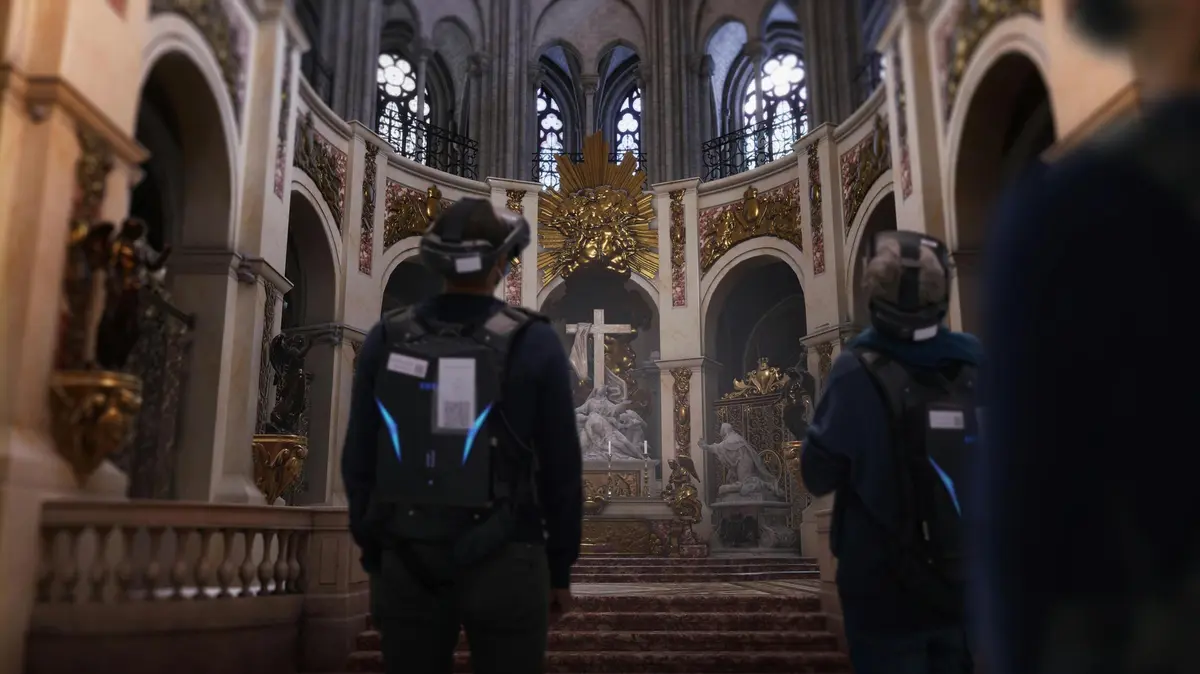 Deux personnes portant un équipement de RV se tiennent à l'intérieur d'une église ornée d'une croix et de statues sur l'autel.