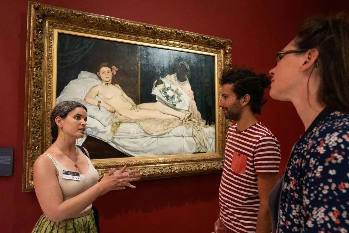 Guide explaining Manet's painting Olympia to two guests