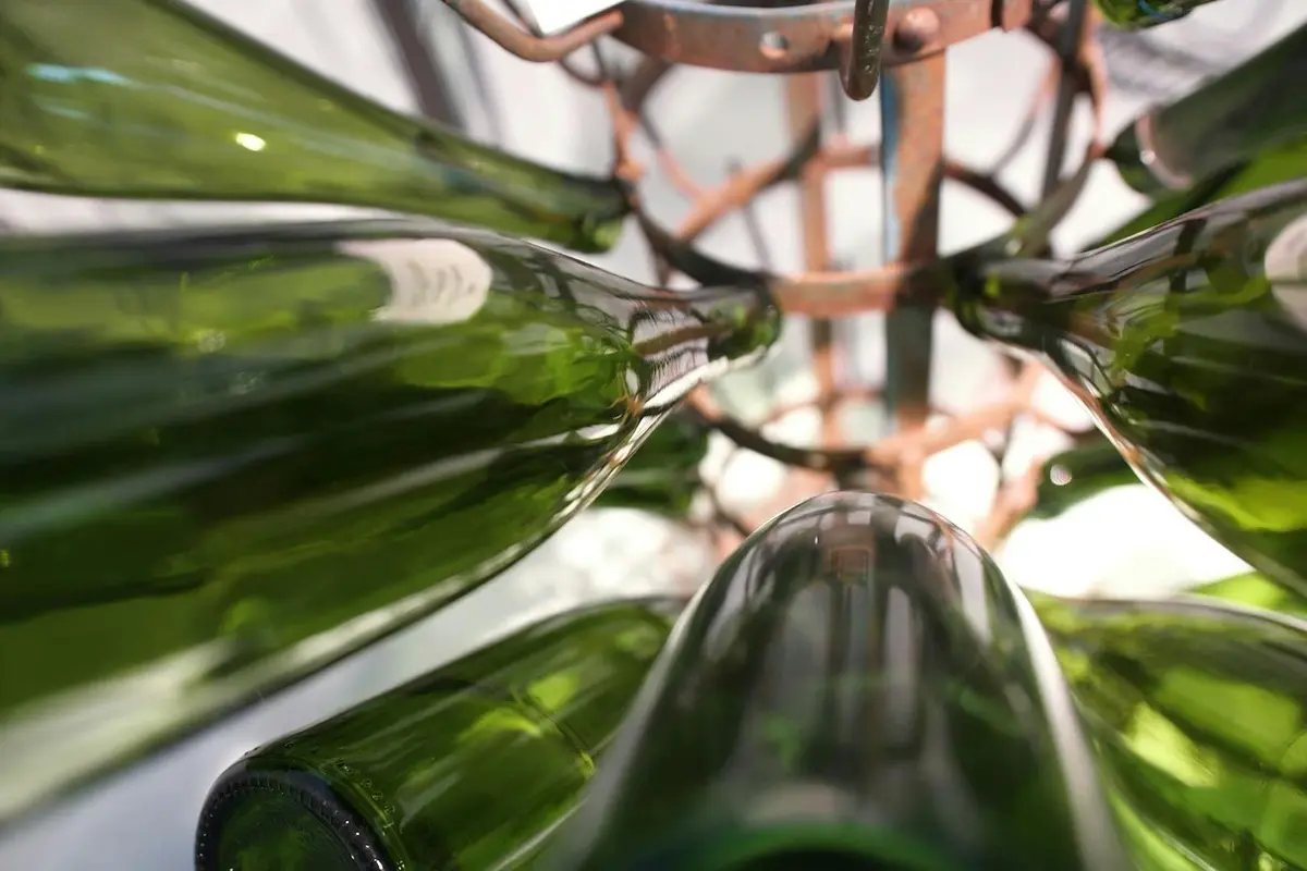 Bouteilles en verre vertes stockées à l'envers dans un casier métallique, vues d'en bas.