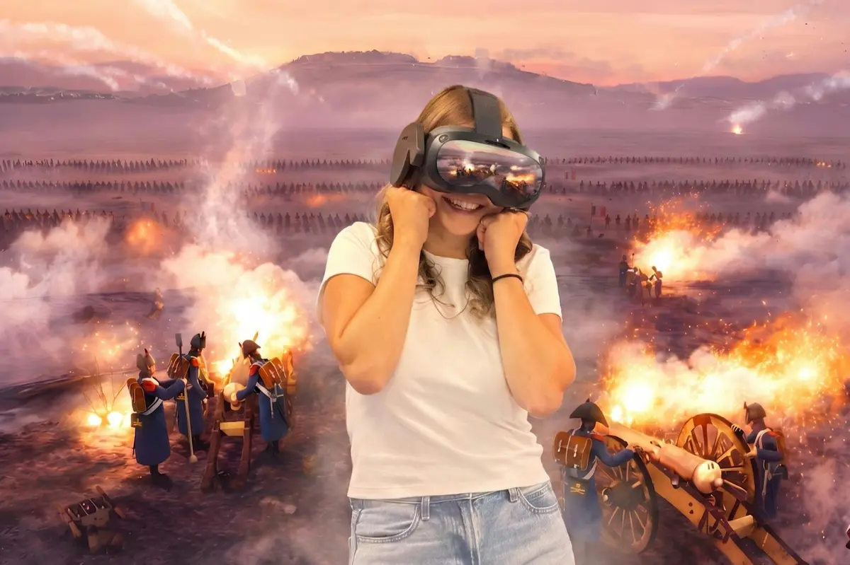 Une personne portant un casque de r&eacute;alit&eacute; virtuelle semble enthousiaste, avec en arri&egrave;re-plan une sc&egrave;ne de bataille historique o&ugrave; l'on voit de la fum&eacute;e et des flammes.