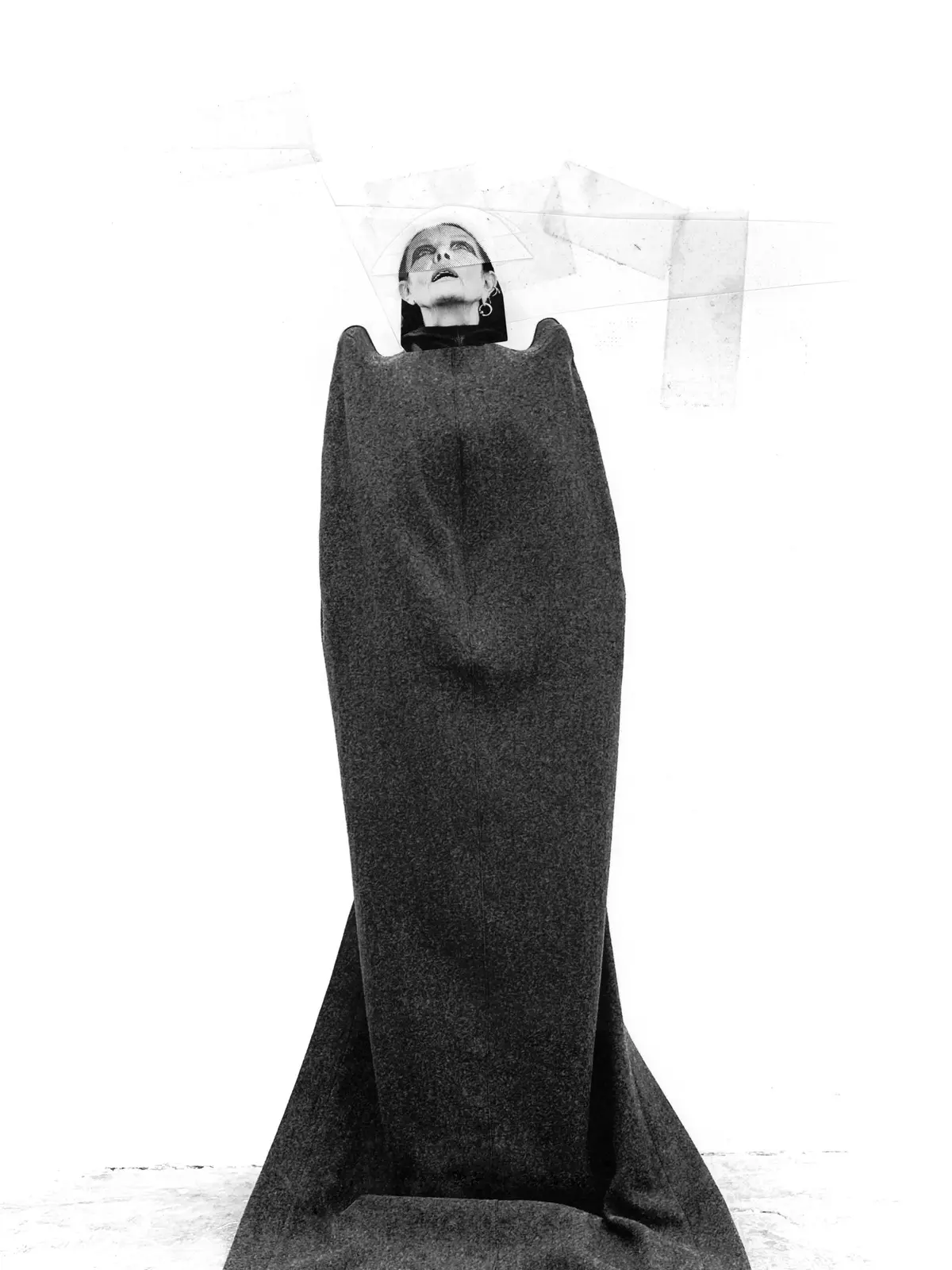 Une personne est enveloppée dans un long tissu sombre et drapé, son visage étant visible au sommet et regardant vers le haut.