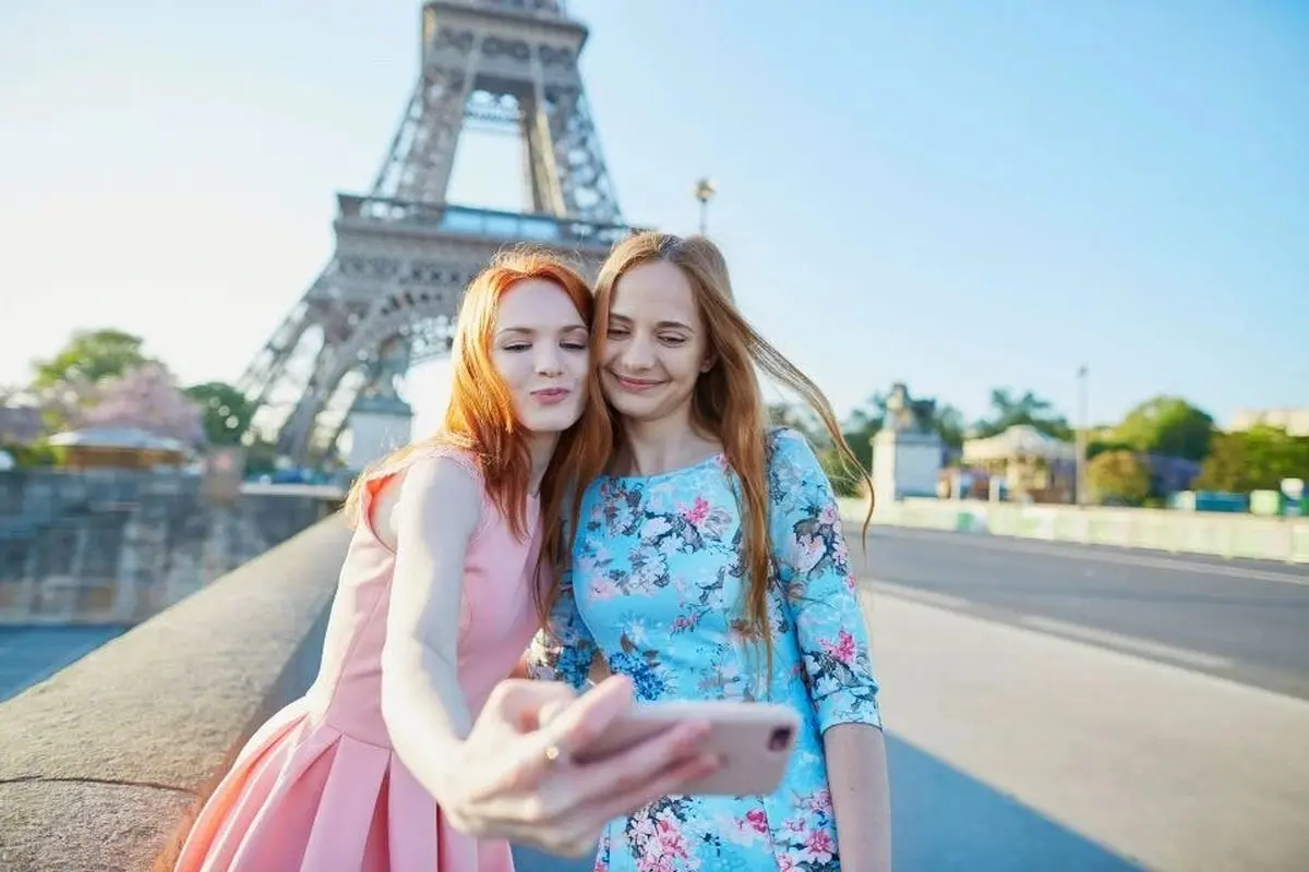 Two tourists taking a selfie at the Eiffel Tower